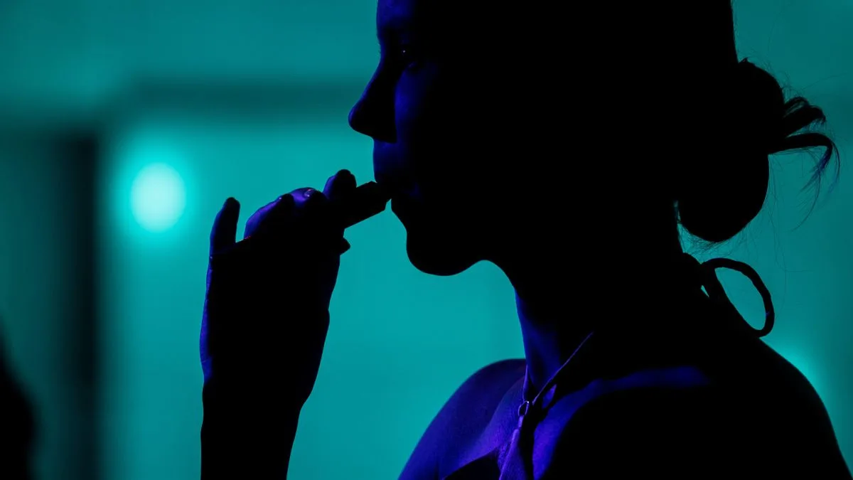 Padres con hijos adolescentes conversando en una terraza al aire libre, con paquetes de cigarrillos y vapers visibles sobre